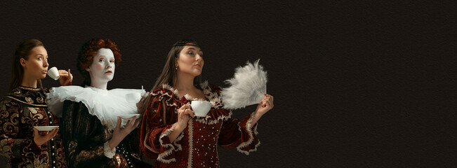 Coffee break for queens. Medieval people as a royalty persons in vintage clothing on dark background. Concept of comparison of eras, modernity and renaissance, baroque style. Creative collage. Flyer