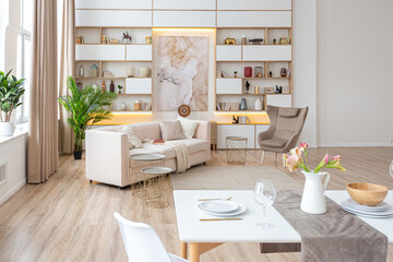 interior design spacious bright studio apartment in Scandinavian style and warm pastel white and beige colors. trendy furniture in the living area and modern details in the kitchen area.