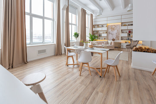 interior design spacious bright studio apartment in Scandinavian style and warm pastel white and beige colors. trendy furniture in the living area and modern details in the kitchen area.