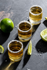 shots of gold Mexican tequila with lime and salt. Alcoholic Mexican national drink. vertical image