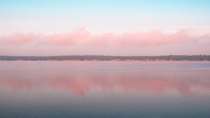 Panoramic reflection of pink clouds on a foggy morning at Saylorville Lake, Iowa. Blue hour, cotton candy clouds, sunrise in the Midwest, USA. 
