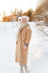 Cheerful girl in warm clothes walking outdoors near the beautiful forest