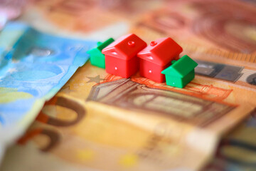 table covered with Euro banknotes with houses on top. Real estate investment concept	
