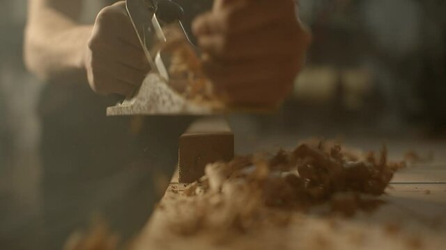 A closeup of a carpenter with a planer at work in the workshop. High quality 4k footage.