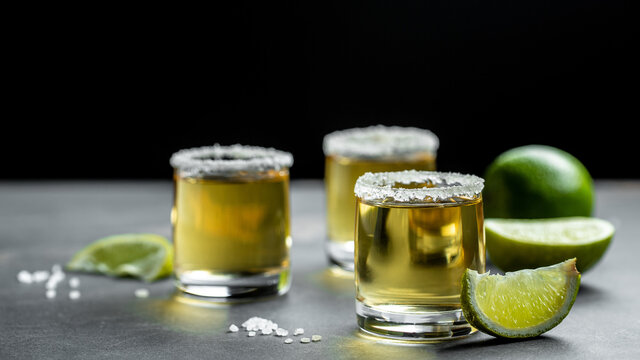 shots of Mexican Gold Tequila with lime and salt on stone background. concept luxury drink. Alcoholic drink. Long banner format