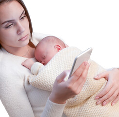 young mother with her sleeping newborn baby sitting and looking at her smartphone