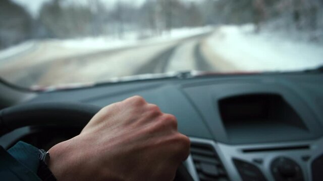 The driver's hand drives a car on a winter road. Moves to the crossroads, makes a turn. Transportation of passengers using a transport vehicle.