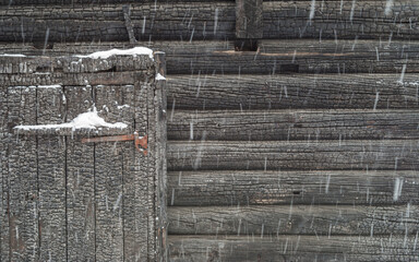 Swing door and a fragment of the facade of an old burnt house during a heavy snowfall