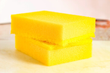 Household sponges of yellow color on a light background.