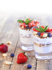 Two glasses of strawberry parfait made from fresh fruit, yogurt, blueberries, flax seeds and muesli on a wooden background. Healthy Eating Concept