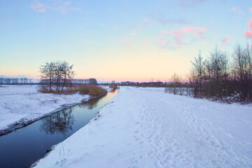 Winter landscape in The Netherlands with beautiful colored sunset sky and fresh white snow, beauty nature background