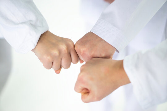 Young people  in kimono  putting their fists together as symbol of unity, closeup .sport  concept  . Martial arts school .
