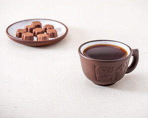 Black coffee and chocolates, ceramic dishes on a white table