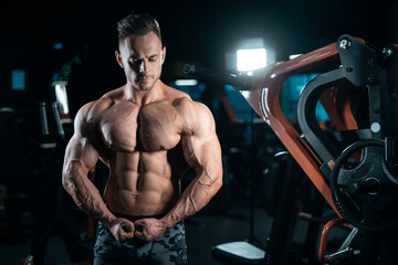 young athletic sportsman bodybuilder with muscle perfect body posing in gym