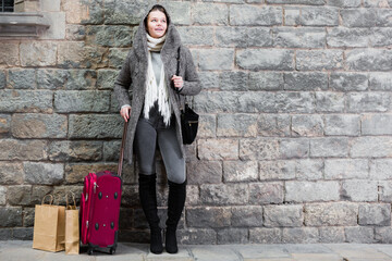 Fototapeta na wymiar teenager girl with baggage in the historical city in hood near wall