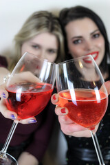 Two girls toasting to celebrate an event, focus on the glasses 