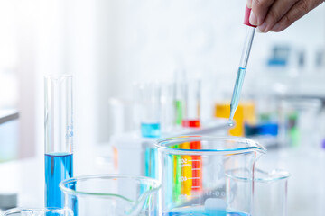 Scientist with a pipette analyzes dropping colored liquid to extract the DNA and molecules in the test tubes for reaction testing in chemical laboratory.