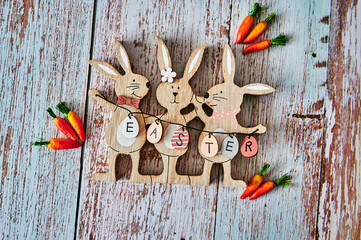 Three wooden Easter bunnies with decoration and the text Easter written on eggs.