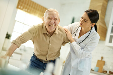 Worried medical worker assisting elderly man with getting up