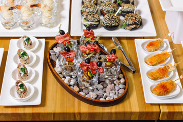 Banquet table with snacks, delicacies, beverages and desserts. On-site service. Luxury catering.