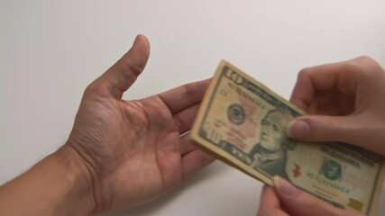 A caucasian woman's hands gives American bills to a Latin American man's hand, and the man clenches the money away. (Camera Used: Canon C300)