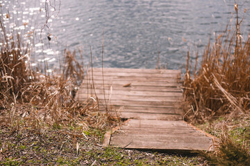 spring landscape, wooden pier and dry reeds on the river