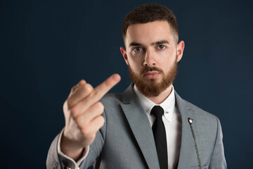 Serious young businessman showing obscene sign