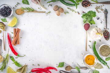 Fresh herbs, dried colorful spices. Cooking background flatlay with variety spices, herbs pepper, vanilla bean, cinnamon, basil, rosemary, chilli red green peppers, mint, parsley White table top view
