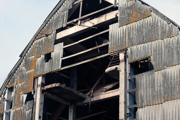 Facade of an old abandoned aircraft hangar is covered with slate.