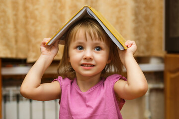 little smiles cute girl with an open book on her head