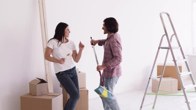Happy young family singing dancing together with work tools during apartment redecoration and home construction