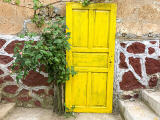 Fototapeta na wymiar yellow painted wooden door on the wall of an old house