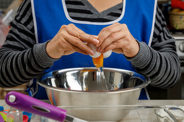 Agregando un huevo a un recipiente, para preparar un panque de plátano. Concepto de repostería en...