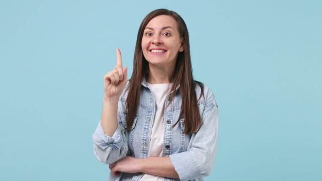 Excited insighted smart proactive young woman 30s years old in denim jacket white t-shirt look around thinks scratches at temple comes up with ideas raised finger up isolated on pastel blue background