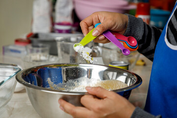 Agregando levadura con una cuchara medidora a un recipiente, para preparar un panque de plátano. Concepto de repostería en casa