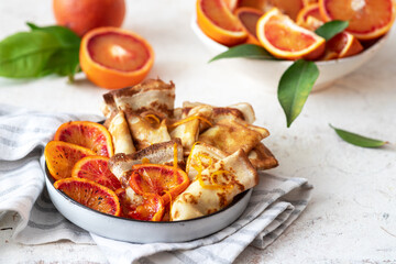 Traditional french crepes suzette with red bloody oranges. Russian bliny