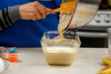 Repostería en casa. Mujer mexicana preparando un panque de plátano, vaciando la masa en el...