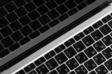 a fragment of a laptop keyboard, black buttons with white letters are reflected in the screen