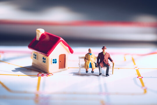 Miniature elderly people sitting with mini house using as job retirement and family concept