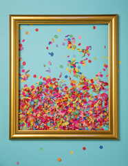 Confetti in golden frame and blue background. Surprice party flat lay concept