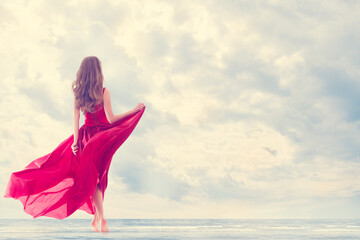 Woman enjoy Sun Sea on Beach. Girl Rear Side Back View in Red Flying Dress on Wind. Happy Holiday...