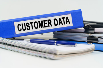 On the table are a notebook, a pen, documents and a folder with the inscription - CUSTOMER DATA