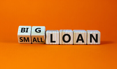 Big or small loan symbol. Turned wooden cubes and changed words 'small loan' to 'big loan'. Beautiful orange table, orange background, copy space. Business and big or small loan concept.