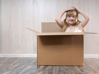 Funny child dreams of a new home sitting in a cardboard box