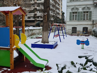 Empty closed modern playground covered with snow. Day view of a recreation area without children or crowd, on a white frozen ground.