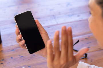 Caucasian woman using smartphone on video call at home, waving