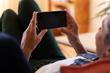 Caucasian woman using smartphone lying on sofa at home