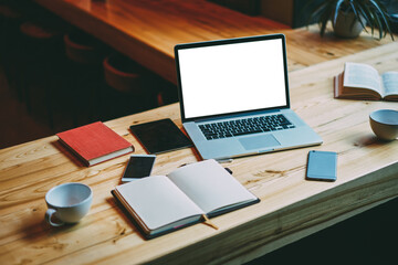 Laptop with smartphones and cups on wooden table