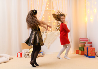 girls play and dance, home interior decorated with festive lights and gifts