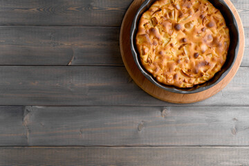 Apple pie in a round shape on a wooden background. Apple charlotte